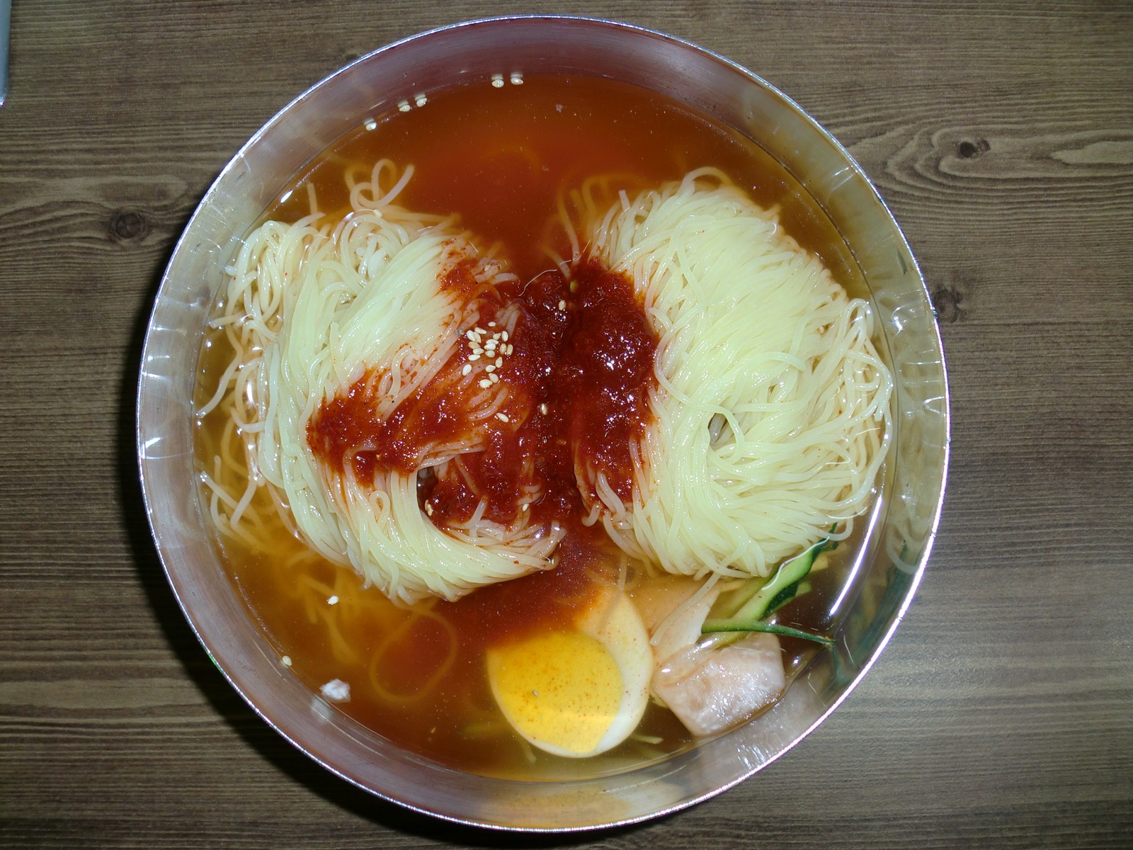 밀면 그릇에 담긴 밀국수와 붉은 양념, 달걀 고명