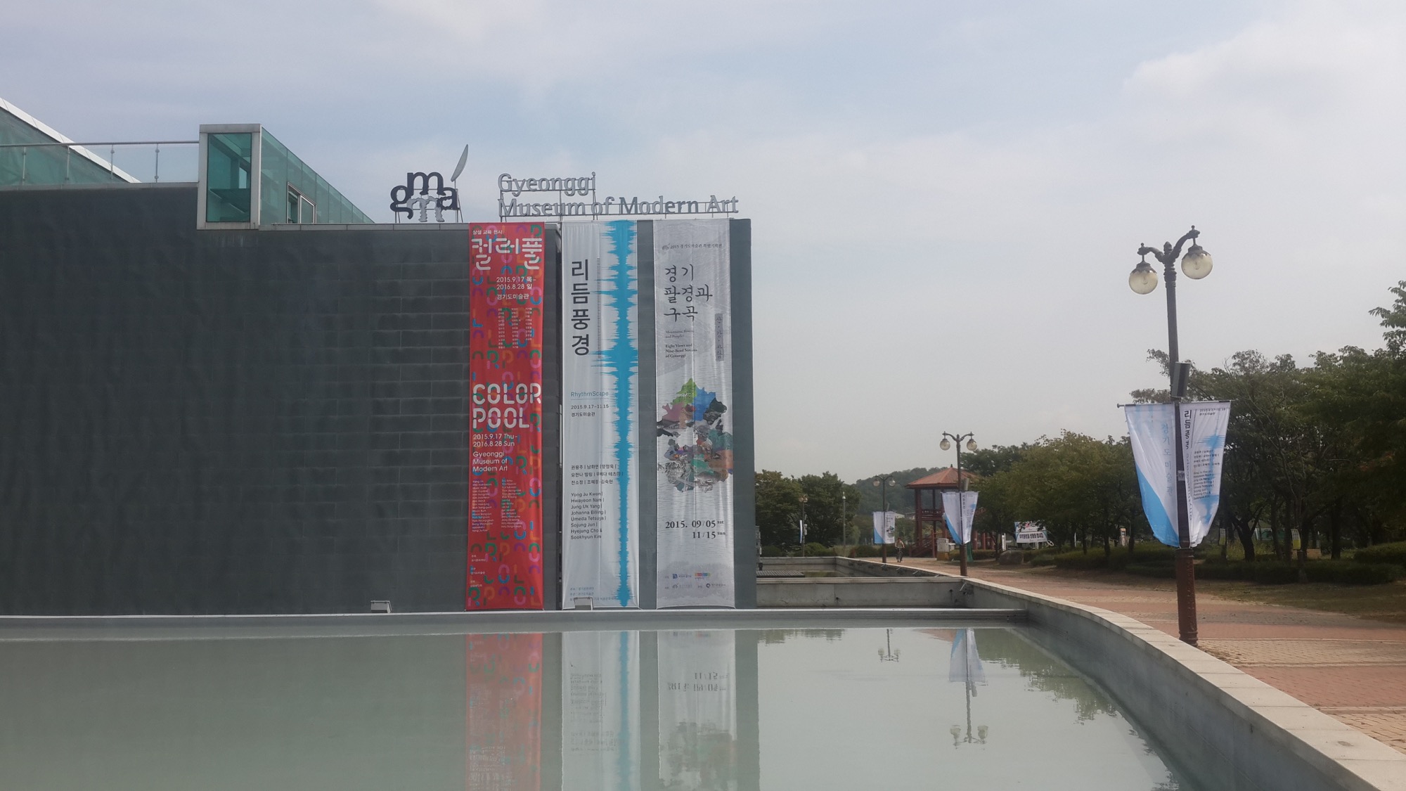 A grey museum wall and vertical banners reflected in a pool
