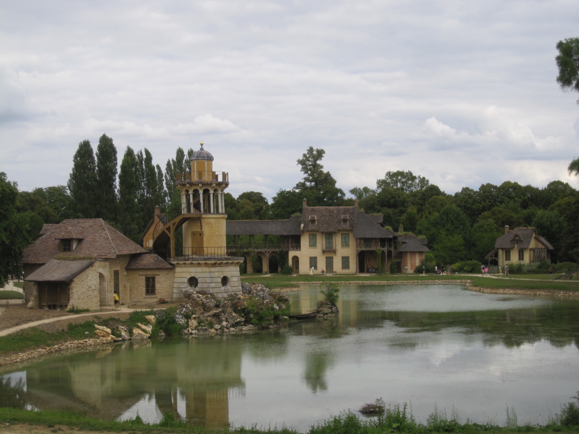 Cottages and a tower beyond a pond at the Queen’s Hamlet, Versailles