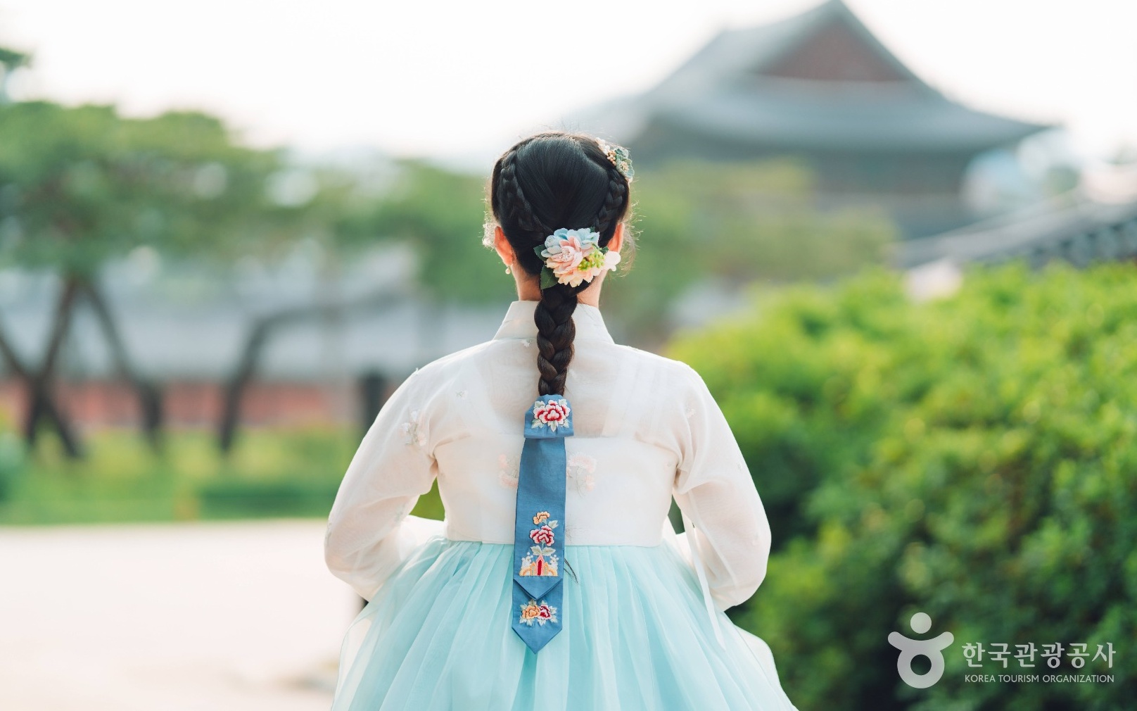한복을 입은 사람의 땋은 머리에 꽃 장식과 긴 자수 댕기가 달려 있다.