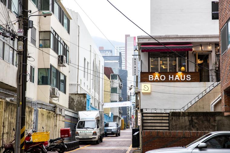 좁은 골목 오른쪽 건물 2층에 BAO HAUS 간판이 있고, 골목에 소형 트럭이 서 있다.