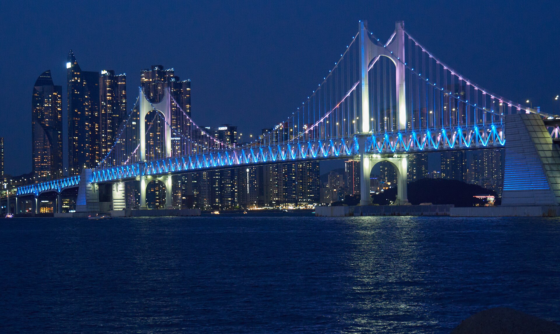 Gwangan Bridge in blue lights with high-rise apartments behind