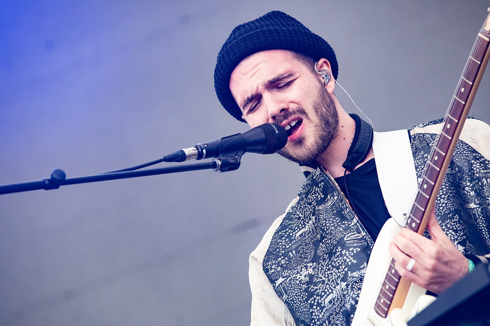 FKJ singing at the mic with a white guitar strap