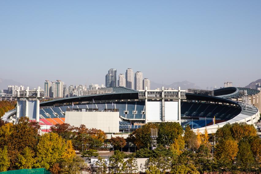 가을 나무 너머로 보이는 잠실야구장 외관과 비어 있는 관중석