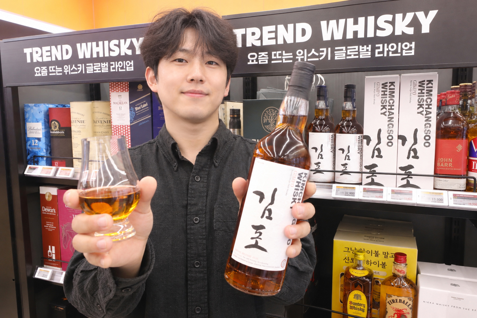 위스키 선반 앞에서 김포 라벨 병과 시음 잔을 든 남성