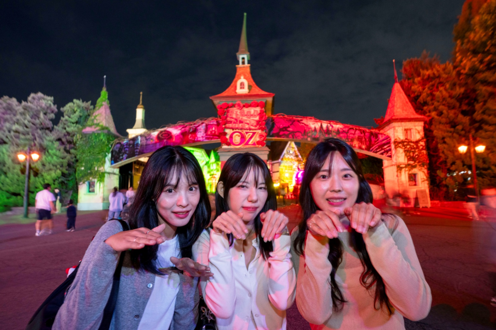Three visitors posing in front of a red-lit archway at night