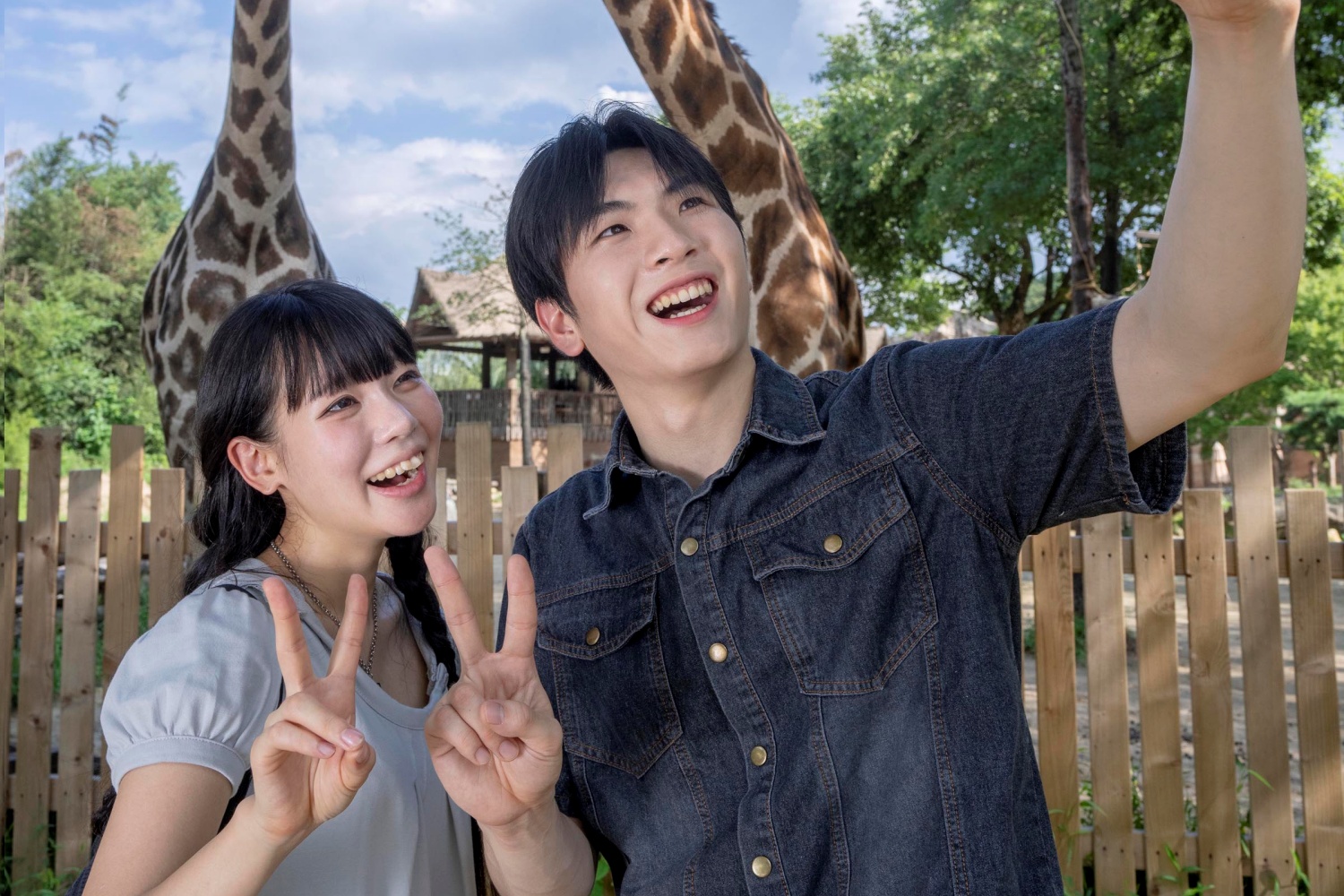 A couple smiling for a selfie in front of giraffes