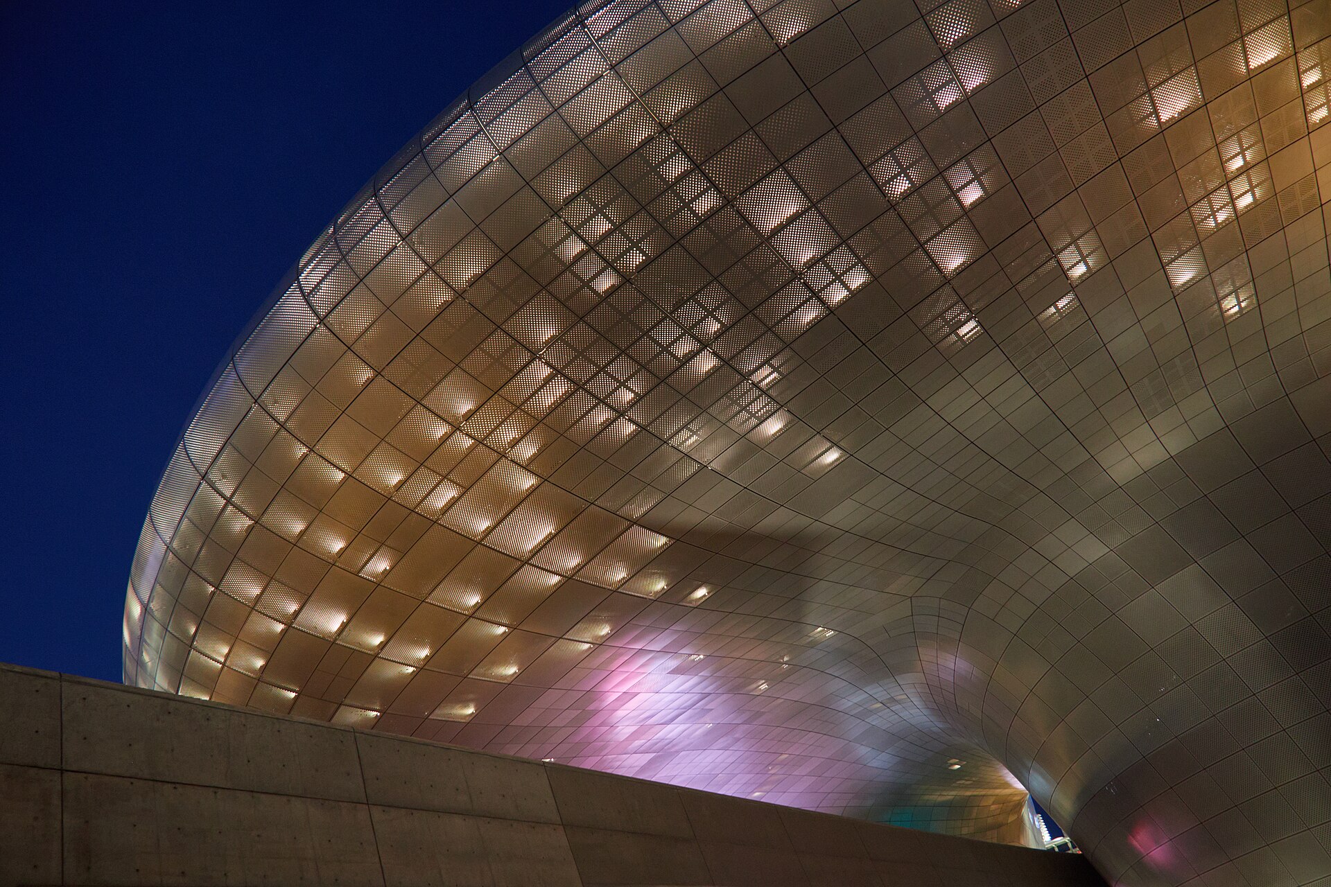 DDP's silver panels washed with pink and amber light under an evening sky