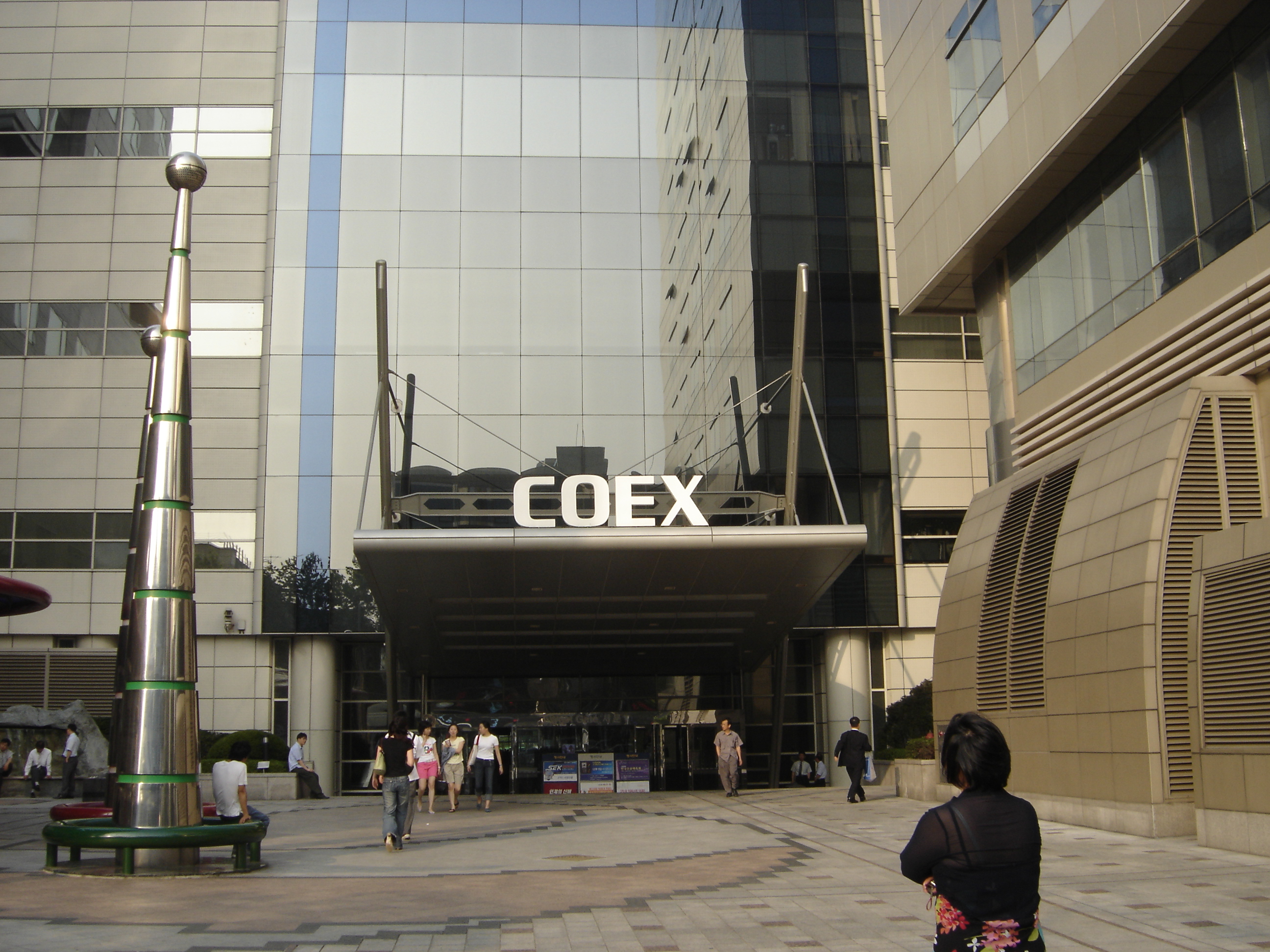 A 2005 archival photograph of a COEX entrance, with white COEX lettering above a canopy and pedestrians in the forecourt.
