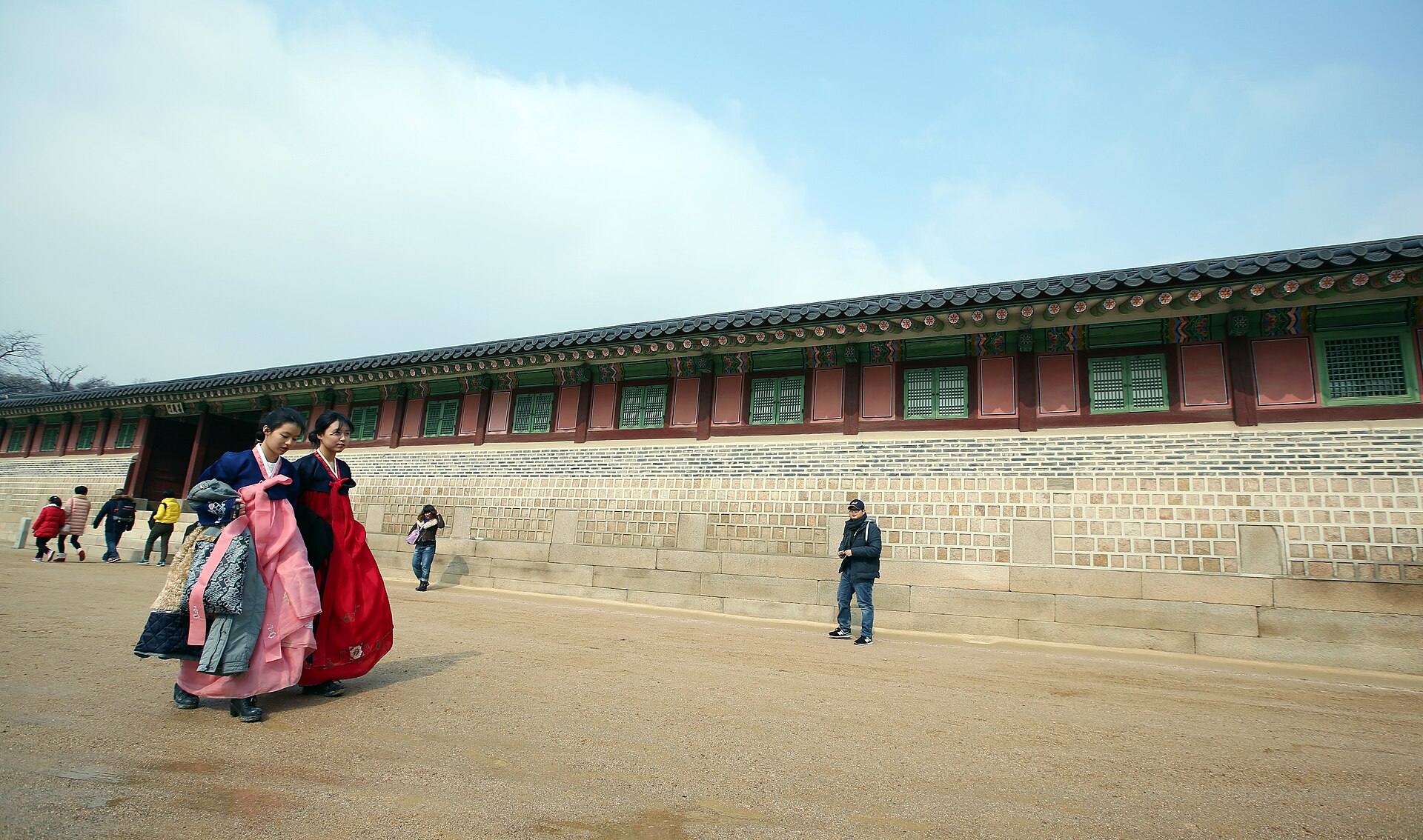 Two visitors in hanbok walking through Gyeongbokgung the day before Seollal