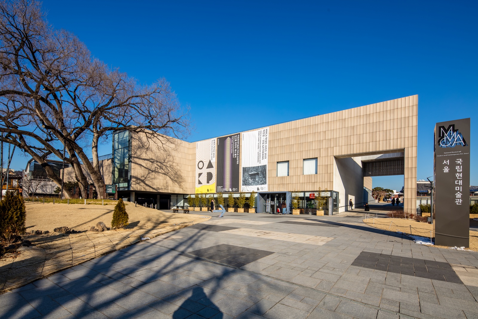 MMCA Seoul's beige stone facade under a blue sky, with the museum sign at right