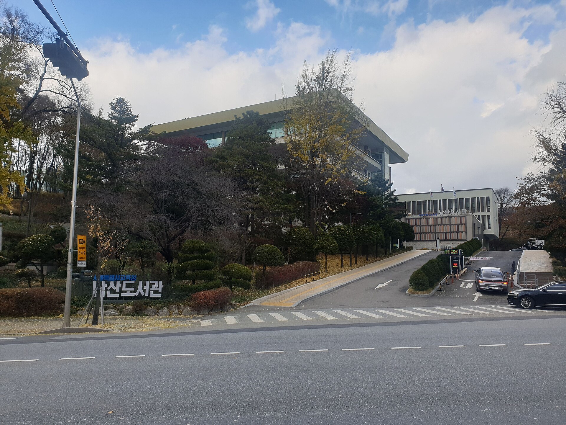 紅葉した木々の向こうの南山図書館と名前の石
