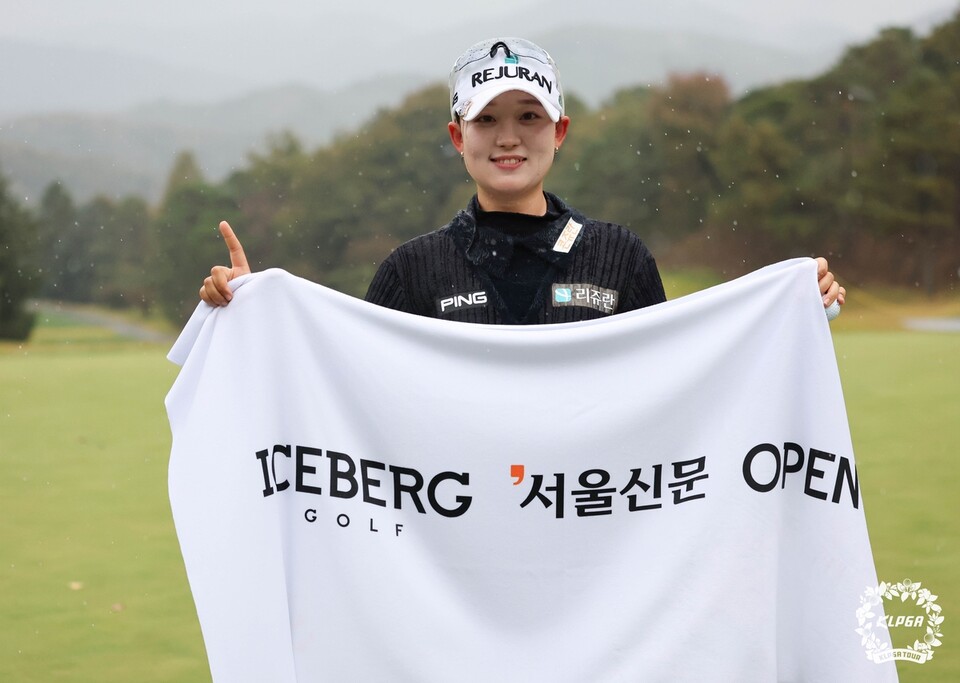 비 내리는 코스를 배경으로 ‘아이스버그골프 서울신문 오픈’ 수건을 펼쳐 든 선수