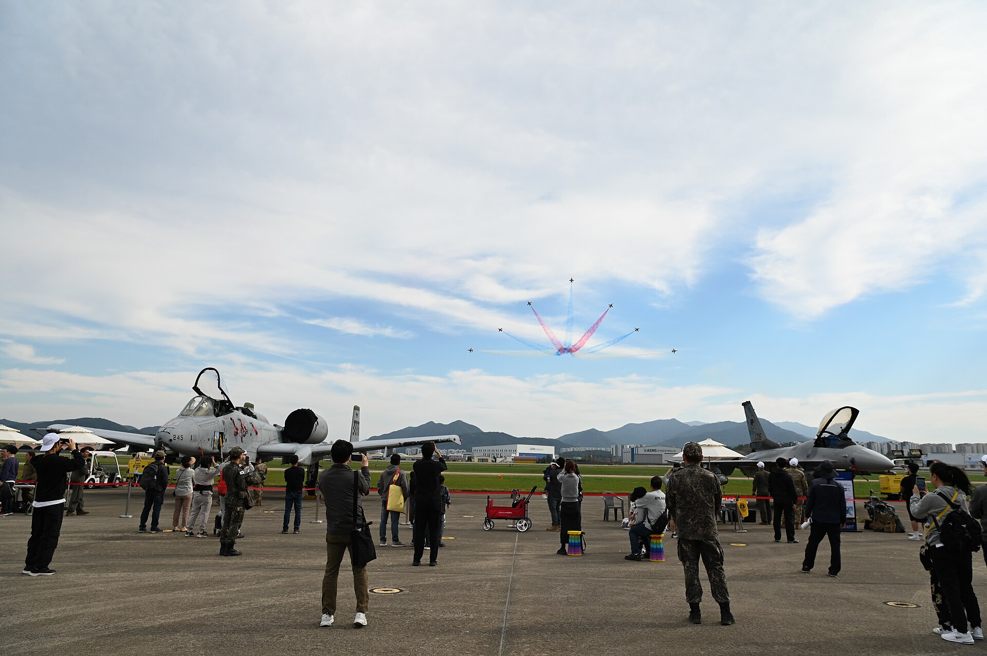 People watching a flight overhead between displayed aircraft