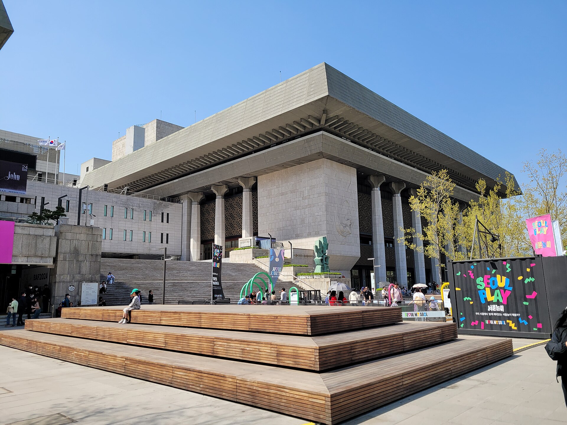 The Sejong Center Grand Theater facade and front steps on a clear day, with a stage-like wooden deck in front