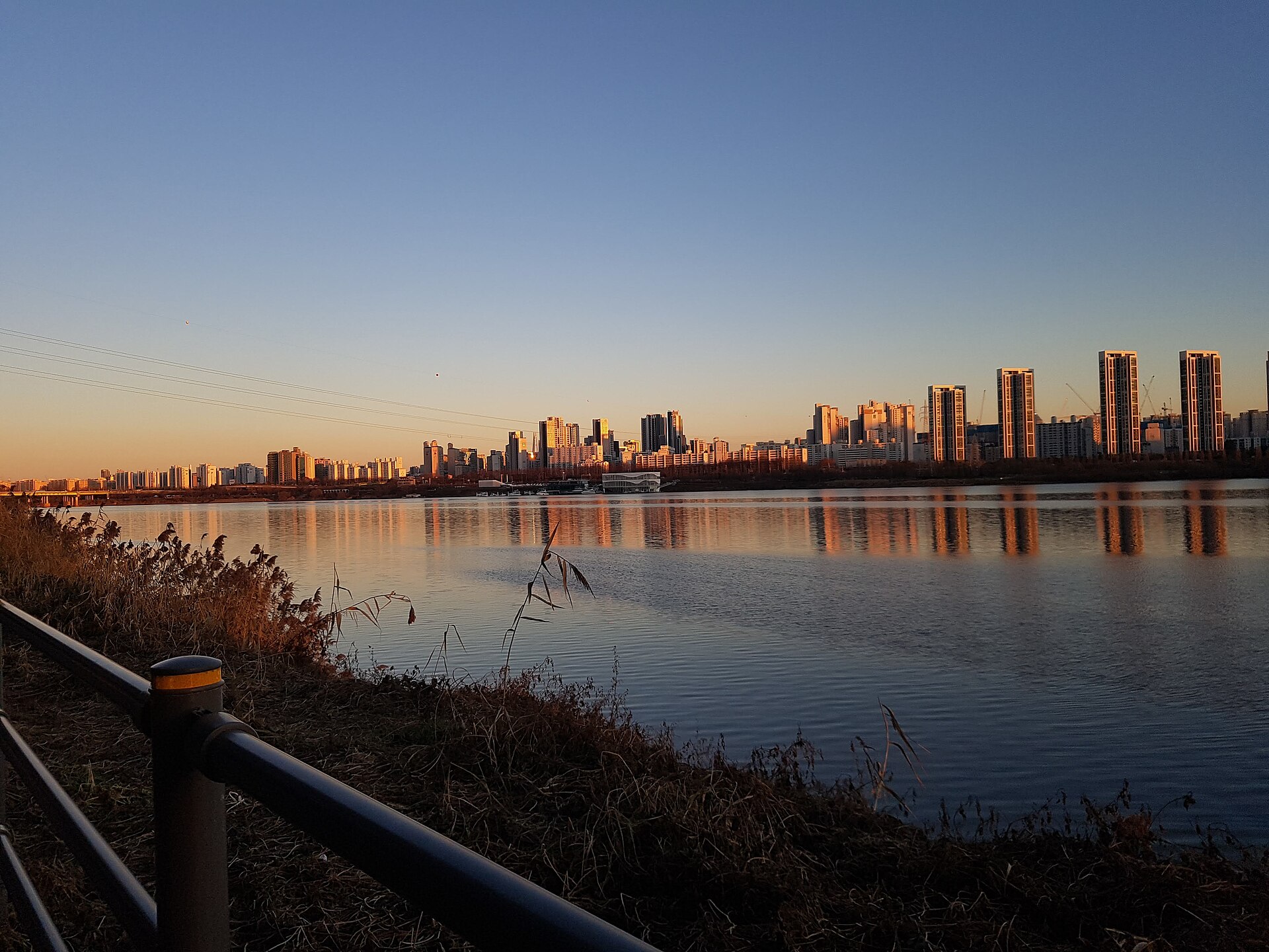 High-rises across the Han River glowing in sunset light, reflected on the water