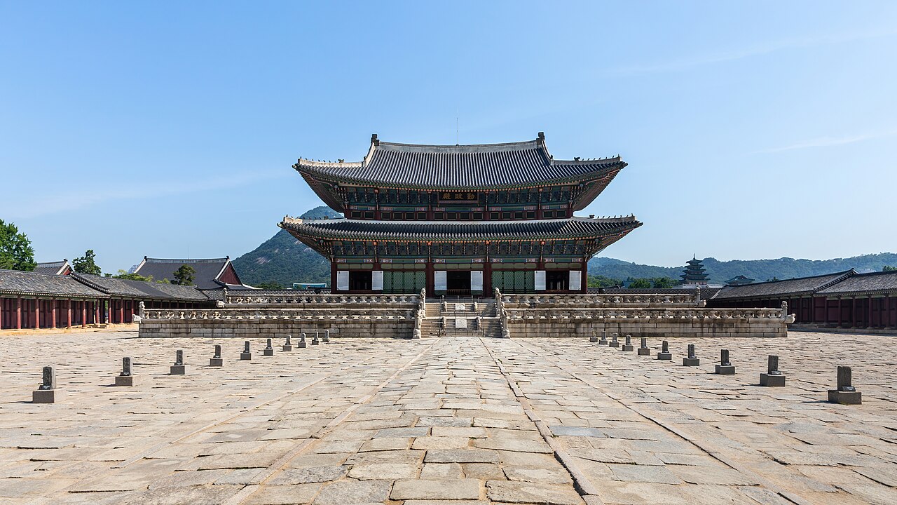푸른 하늘 아래 서울 경복궁 근정전과 돌로 된 앞마당을 정면에서 본 모습