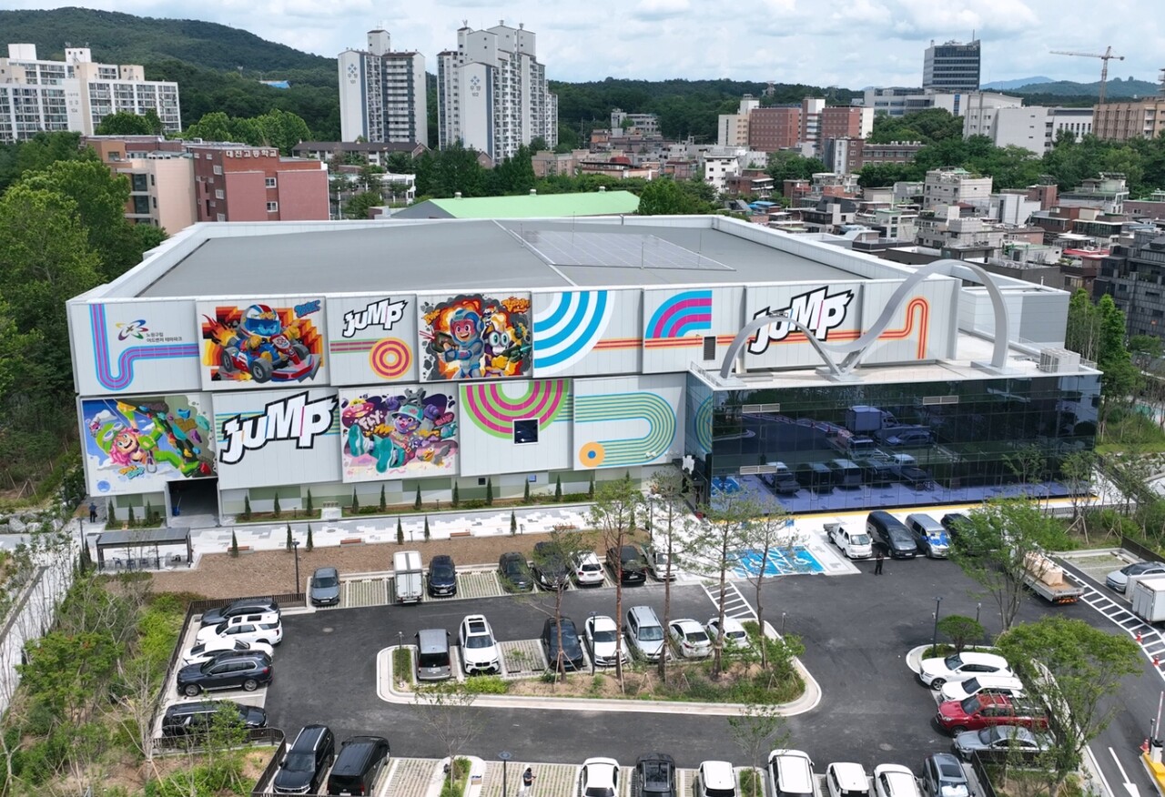 주택가 사이에 서 있는, 외벽에 점프 로고가 큼직한 2층 건물과 앞 주차장