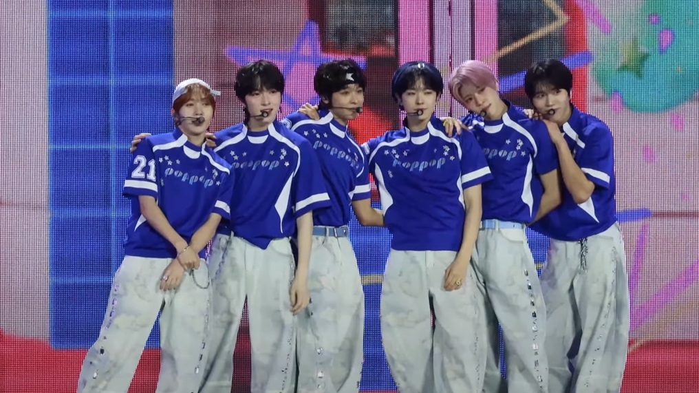 파란색과 흰색 상의와 밝은 청바지를 맞춰 입은 NCT WISH 여섯 멤버가 무대에 나란히 서 있다.