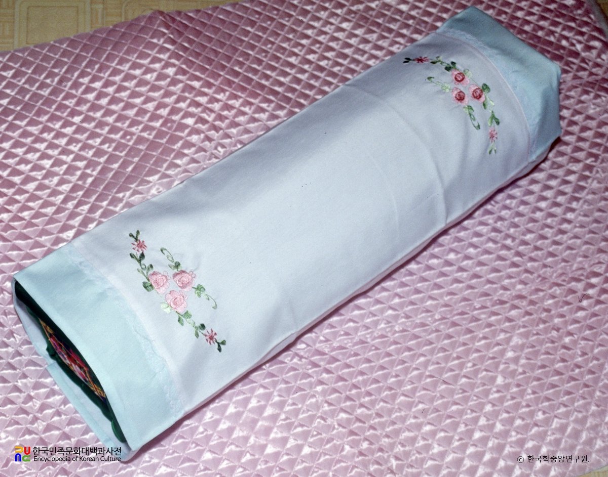 花模様を施した細長い薄青色の布の枕
