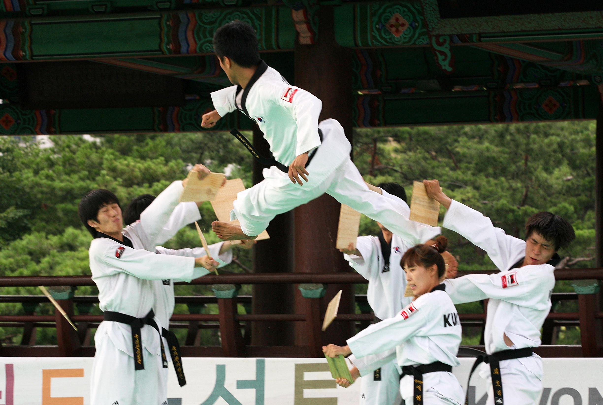 2012년 남산골한옥마을에서 여러 동료가 잡은 송판 사이로 공중 발차기를 하는 국기원 단원
