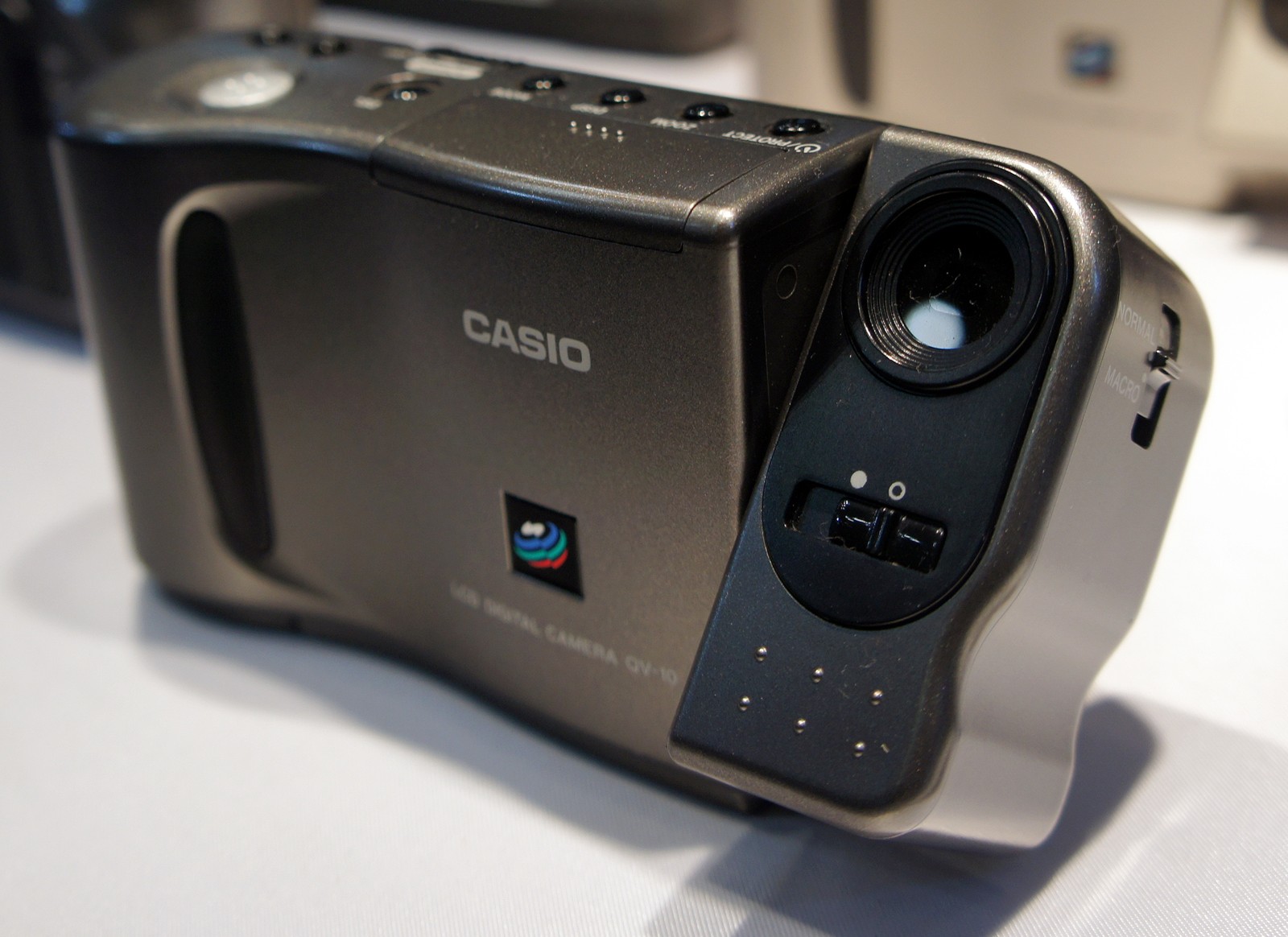 렌즈 부분이 회전하는 검은색 Casio QV-10을 앞쪽에서 본 전시 사진